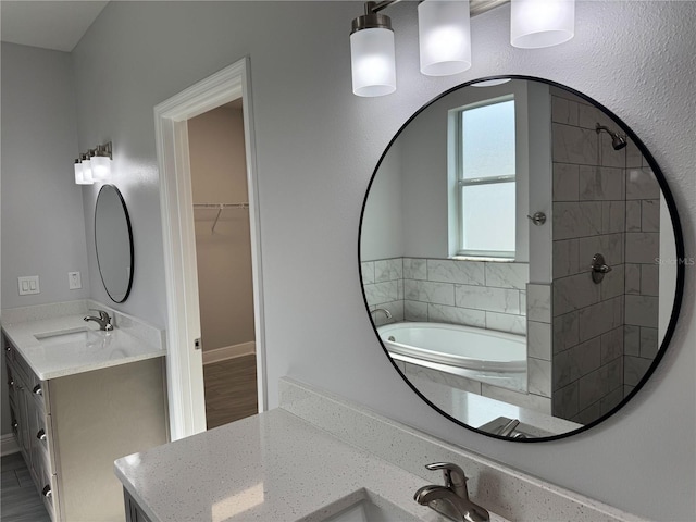 bathroom with a tile shower, a bath, vanity, and a spacious closet