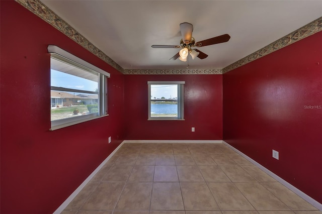 empty room with baseboards, a ceiling fan, and light tile patterned floors