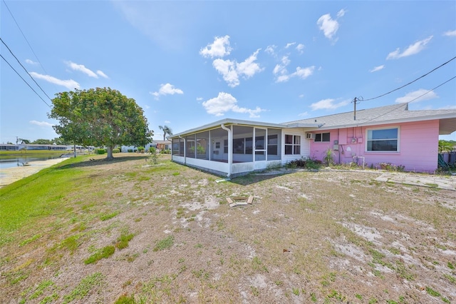 back of property with a water view and a sunroom