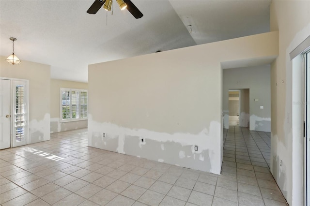 spare room with a ceiling fan, lofted ceiling, and light tile patterned floors