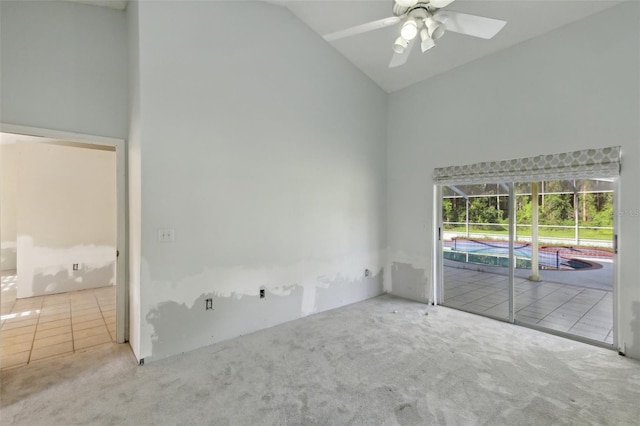 carpeted spare room with ceiling fan, tile patterned floors, and high vaulted ceiling
