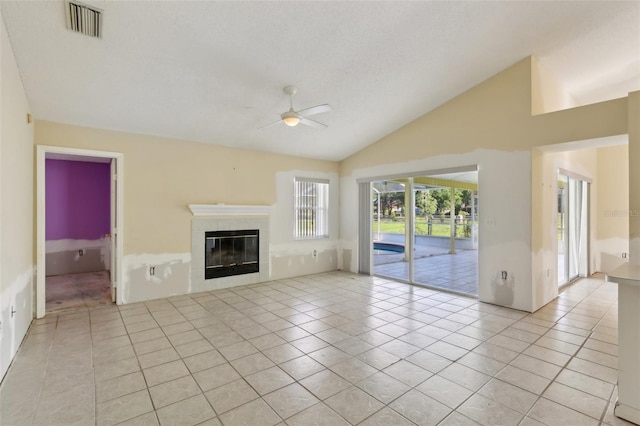 unfurnished living room featuring a tiled fireplace, ceiling fan, light tile patterned floors, and lofted ceiling