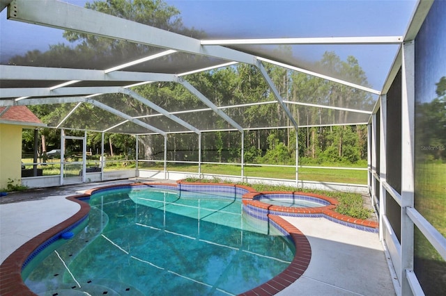 view of swimming pool featuring glass enclosure, a pool with connected hot tub, and a patio area