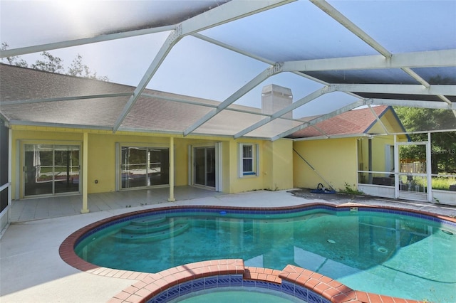 view of pool with glass enclosure, a pool with connected hot tub, and a patio area