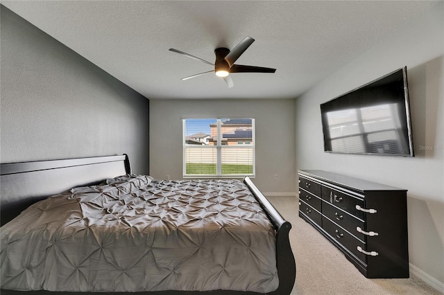 bedroom featuring light carpet, ceiling fan, baseboards, and a textured ceiling