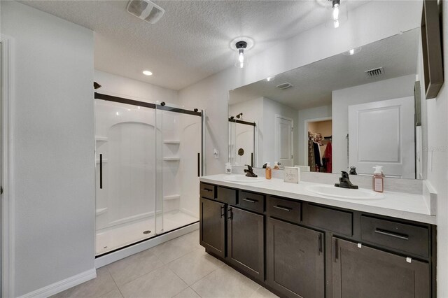 full bath with a stall shower, tile patterned flooring, a textured ceiling, double vanity, and a walk in closet