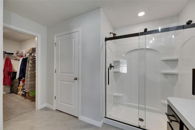bathroom with a shower stall, baseboards, tile patterned floors, and a walk in closet