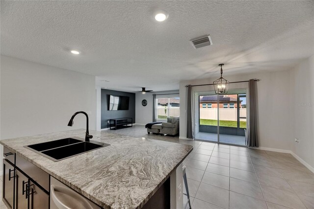 kitchen with a sink, a center island with sink, dishwasher, a textured ceiling, and open floor plan