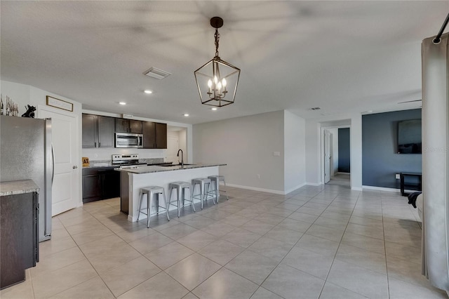 kitchen with appliances with stainless steel finishes, recessed lighting, a chandelier, a center island with sink, and dark brown cabinetry