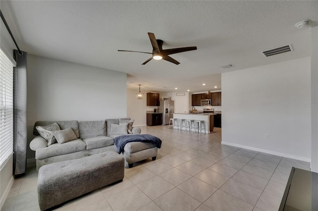 living area featuring ceiling fan, baseboards, light tile patterned flooring, recessed lighting, and a textured ceiling