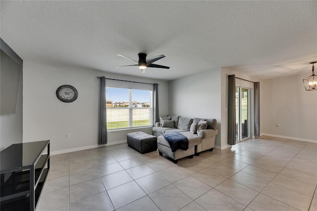 living room featuring a chandelier, a textured ceiling, light tile patterned floors, a ceiling fan, and baseboards