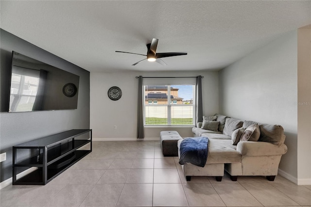 living area with ceiling fan, a textured ceiling, light tile patterned floors, and baseboards