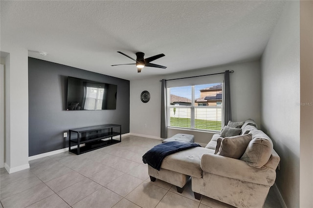 living room featuring ceiling fan, baseboards, a textured ceiling, and light tile patterned flooring