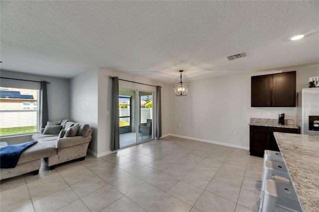 kitchen with open floor plan, dark brown cabinets, a chandelier, stainless steel refrigerator with ice dispenser, and light tile patterned floors