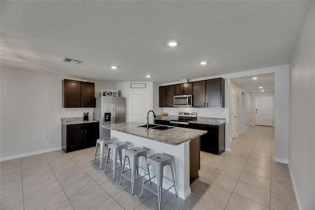 kitchen with a sink, appliances with stainless steel finishes, a breakfast bar area, recessed lighting, and baseboards