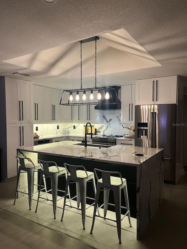 926 Eagle Ln, Apollo Beach, FL 33572 - kitchen featuring a textured ceiling, a large island, a sink, light stone counters, and extractor fan