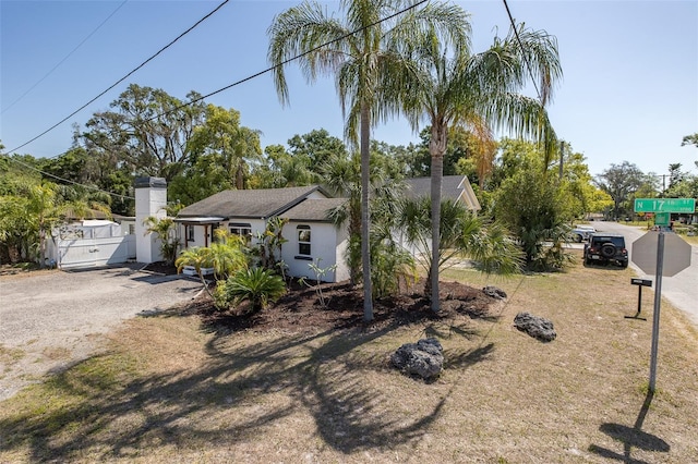 view of front of property featuring fence, a chimney, driveway, and stucco siding