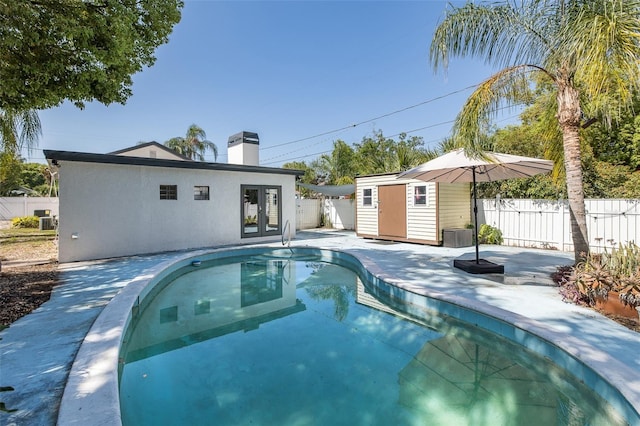 view of pool with fence, a fenced in pool, a patio area, french doors, and an outdoor structure