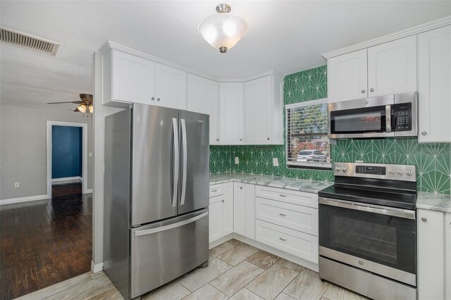 kitchen featuring stainless steel appliances, visible vents, white cabinetry, and tasteful backsplash