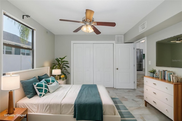 bedroom featuring freestanding refrigerator, a closet, marble finish floor, and visible vents