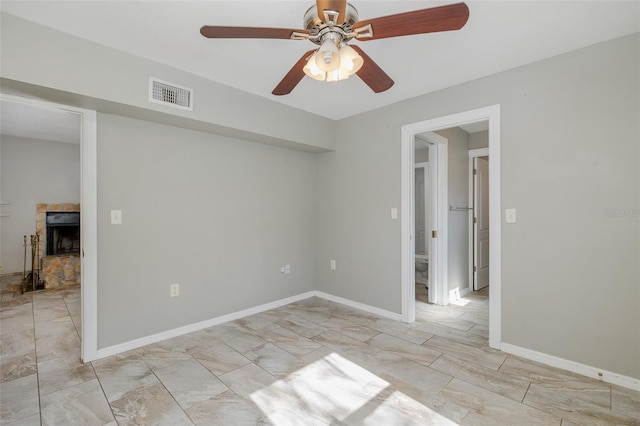 empty room featuring baseboards, a fireplace, a ceiling fan, and visible vents