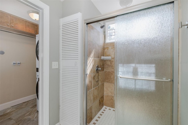 bathroom with a stall shower, baseboards, stacked washer / dryer, and a closet