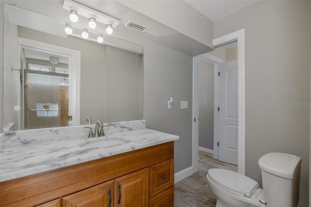 full bathroom featuring visible vents, vanity, toilet, baseboards, and a shower stall