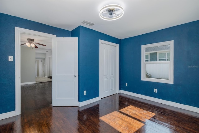 unfurnished bedroom with wood-type flooring, baseboards, visible vents, and a closet
