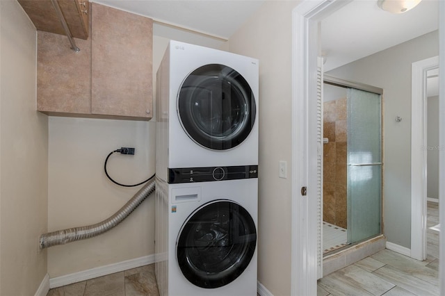 laundry room featuring baseboards, stacked washer and dryer, and cabinet space