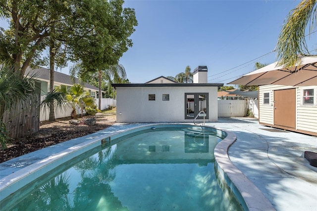 view of pool featuring an outdoor structure, a fenced backyard, french doors, a fenced in pool, and a patio area