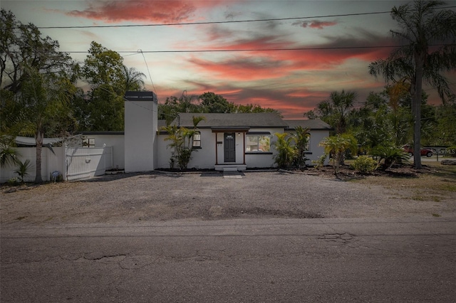 mid-century inspired home with fence, driveway, and a chimney
