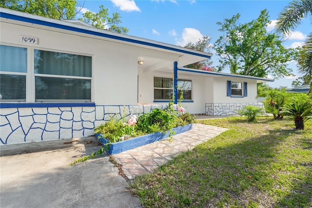 1099 7th Ave NE, Largo, FL 33770 - view of property exterior with a lawn and stucco siding