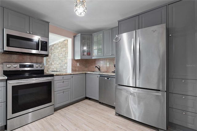 1099 7th Ave NE, Largo, FL 33770 - kitchen with decorative backsplash, gray cabinetry, light stone counters, glass insert cabinets, and stainless steel appliances