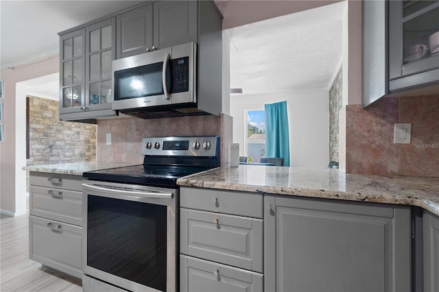 1099 7th Ave NE, Largo, FL 33770 - kitchen with light stone counters, decorative backsplash, gray cabinets, and stainless steel appliances