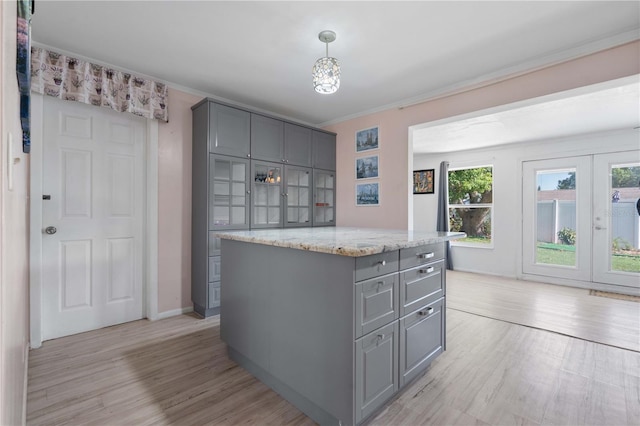 1099 7th Ave NE, Largo, FL 33770 - kitchen with light stone counters, a kitchen island, light wood-style floors, gray cabinets, and french doors
