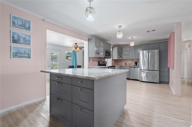 1099 7th Ave NE, Largo, FL 33770 - kitchen featuring appliances with stainless steel finishes, gray cabinets, light wood-style flooring, tasteful backsplash, and glass insert cabinets