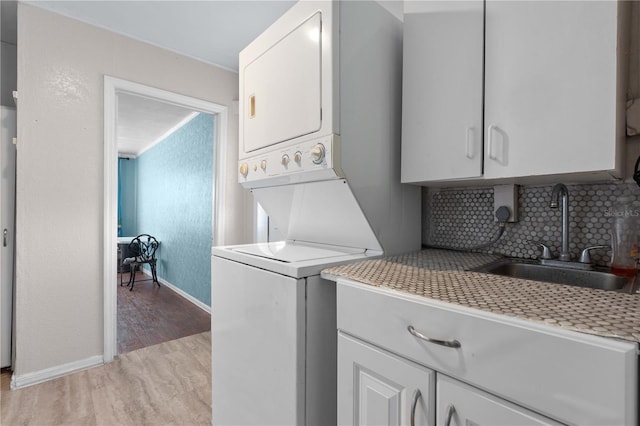 1099 7th Ave NE, Largo, FL 33770 - washroom with cabinet space, a sink, light wood-style floors, baseboards, and stacked washer / dryer