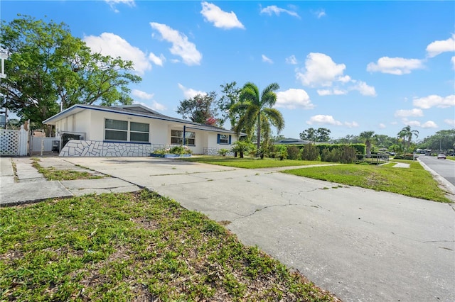 1099 7th Ave NE, Largo, FL 33770 - view of front of property featuring a front lawn, fence, stone siding, stucco siding, and driveway