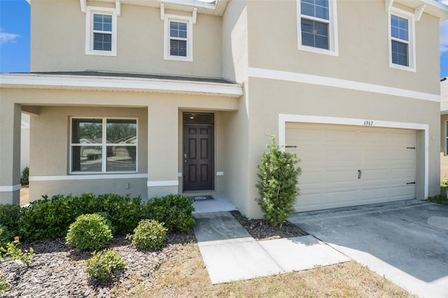 doorway to property featuring an attached garage, driveway, stucco siding, and a porch