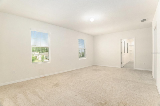 spare room featuring baseboards, visible vents, and carpet