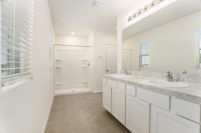 bathroom with a sink, tiled shower, and baseboards