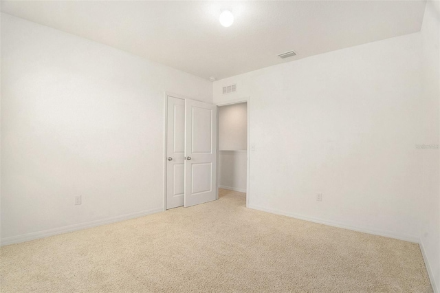 carpeted spare room featuring visible vents and baseboards