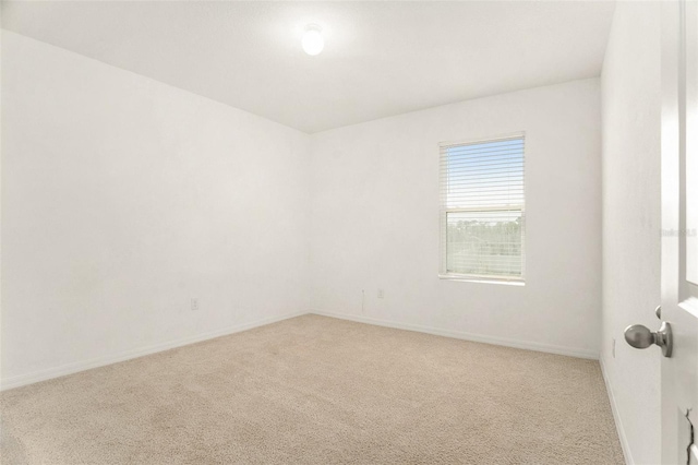 empty room featuring light carpet and baseboards
