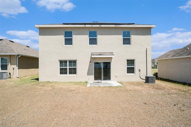 rear view of property featuring solar panels, cooling unit, and stucco siding