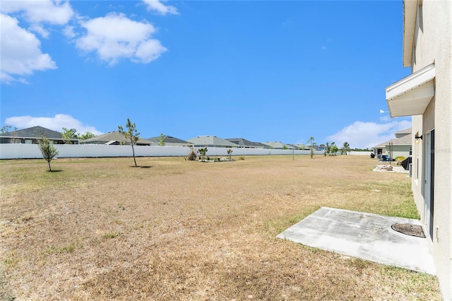 view of yard featuring fence, a patio area, and a residential view