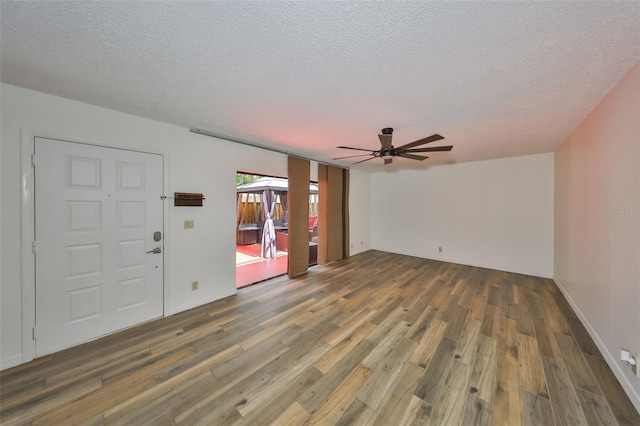 2627 2nd Ct, Palm Harbor, FL 34684 - unfurnished living room with a textured ceiling, a ceiling fan, and wood finished floors