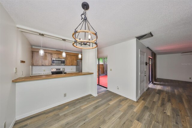 2627 2nd Ct, Palm Harbor, FL 34684 - kitchen with an inviting chandelier, appliances with stainless steel finishes, wood finished floors, and butcher block counters