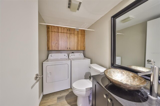 2627 2nd Ct, Palm Harbor, FL 34684 - bathroom featuring independent washer and dryer, vanity, toilet, wood finished floors, and visible vents