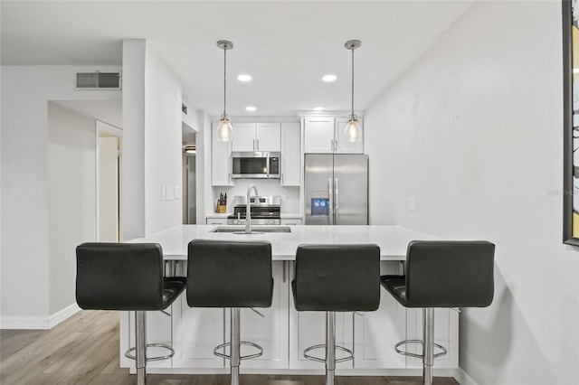 kitchen with appliances with stainless steel finishes, a sink, baseboards, light wood-type flooring, and visible vents