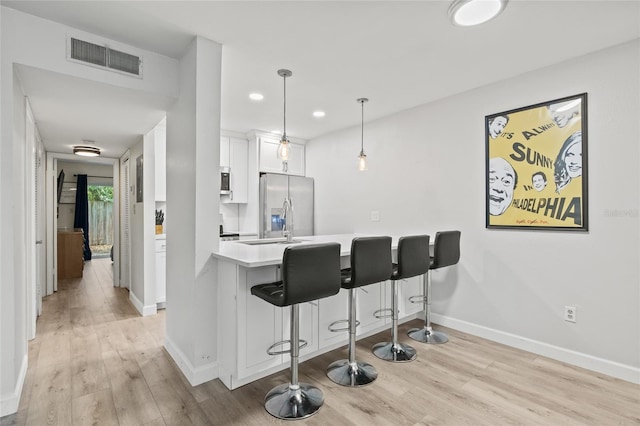 kitchen with visible vents, light wood finished floors, a kitchen breakfast bar, and stainless steel fridge with ice dispenser